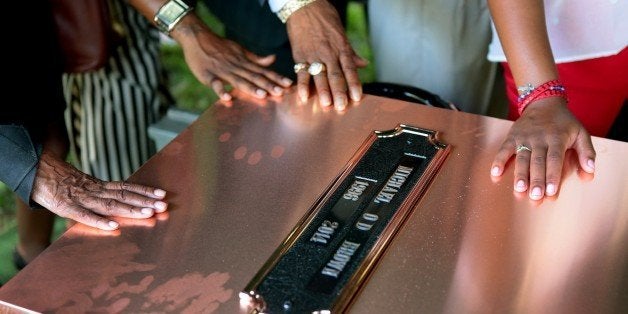 ST. LOUIS, MO - AUGUST 25: Family members touch the copper top of the vault containing the casket of Michael Brown during burial at St. Peters Cemetery on August 25, 2014 in St. Louis Missouri. Michael Brown, an 18 year-old unarmed teenager, was shot and killed by Ferguson Police Officer Darren Wilson in the nearby town of Ferguson, Missouri on August 9. His death caused several days of violent protests along with rioting and looting in Ferguson. (Photo by Robert Cohen-Pool/Getty Images)