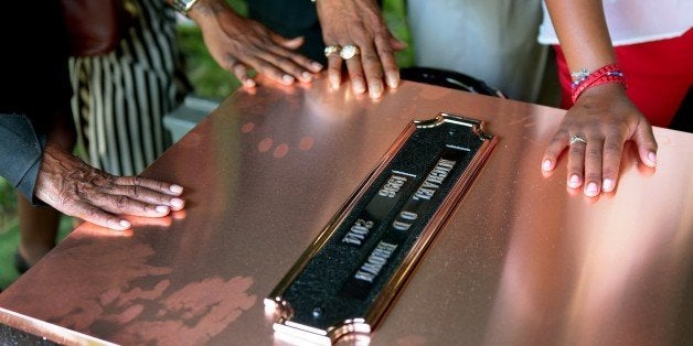 ST. LOUIS, MO - AUGUST 25: Family members touch the copper top of the vault containing the casket of Michael Brown during bur