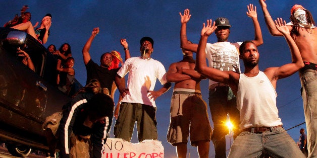 FILE - In this Aug. 17, 2014 file photo, people protest for Michael Brown, who was killed by a police officer in Ferguson, Mo