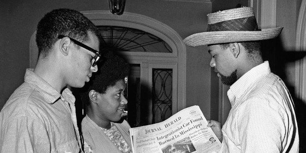 FILE - This photo made June 24, 1964, shows Ed Wilson, left, Peggy Sharp, and Cordell Reagan reading of the finding of the burned car of three civil rights workers in Mississippi. The three were among hundreds of civil rights activists who gathered there in June 1964 to train for voter registration of blacks in Mississippi. (AP Photo/Eugene Smith)