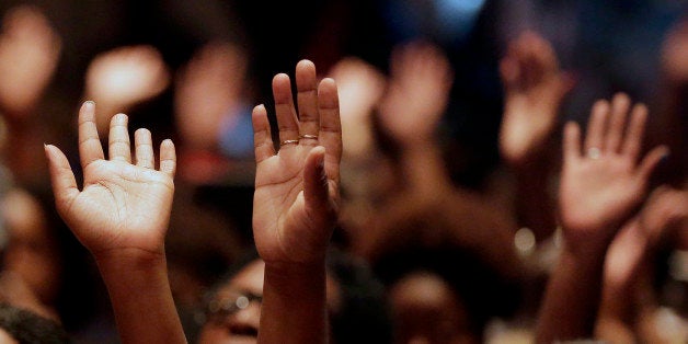 FILE - In this Aug. 17, 2014 file photo, people raise their hands during a rally at Greater Grace Church for Michael Brown, who was killed by police, last Saturday in Ferguson, Mo. With a grand jury announcement in the Ferguson case drawing near, many churches plan to offer prayer, shelter, food and a sanctuary for protesters, residents, students and others affected by potential unrest. (AP Photo/Charlie Riedel, File)