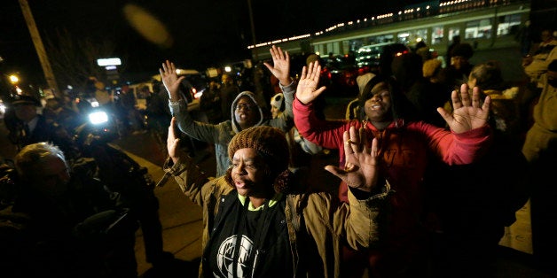 Barbara Jones joined by other protesters raise their hands up in the air as they protest Monday, Nov. 24, 2014, in Ferguson,