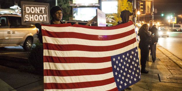 FERGUSON, MO - OCTOBER 10 : Protestors hold an American flag upside down, universal sign for distress, outside the Ferguson Police Station on October 10, 2014 in Ferguson, United States. (Photo by Samuel Corum/Anadolu Agency/Getty Images)