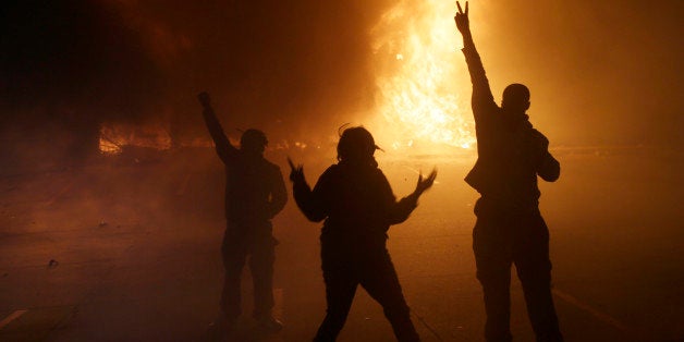 People watch as stores burn down Tuesday, Nov. 25, 2014, in Ferguson, Mo. A grand jury has decided not to indict Ferguson police officer Darren Wilson in the death of Michael Brown, the unarmed, black 18-year-old whose fatal shooting sparked sometimes violent protests. (AP Photo/David Goldman)