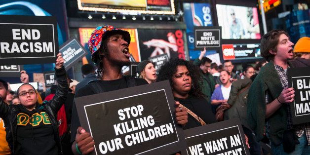 Protestors hold signs during a demonstration in Times Square after the announcement of the grand jury decision not to indict Ferguson police officer Darren Wilson in the fatal shooting of Michael Brown, an unarmed black 18-year-old, Monday, Nov. 24, 2014, in New York. (AP Photo/John Minchillo)