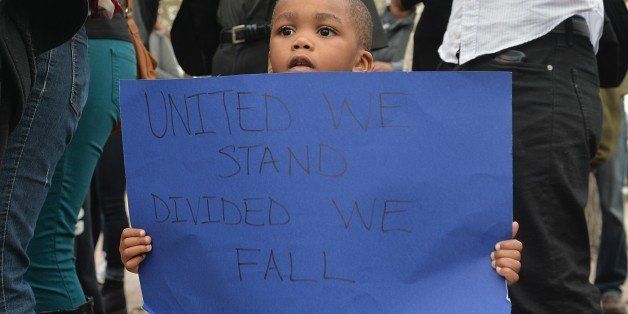 A child holds a sign as demonstrators protest outside the Edward Jones Dome in downtown St. Louis, Missouri on November 30, 2014. Demonstrators marched through the streets of St. Louis that eventually led to clashes with police officers and fans from an American Football game between the St. Louis Rams and Oakland Raiders. Protests have continued following a grand jury decision not to charge a white police officer for the shooting death last of an unarmed black teenager. AFP PHOTO/Michael B. Thomas (Photo credit should read Michael B. Thomas/AFP/Getty Images)