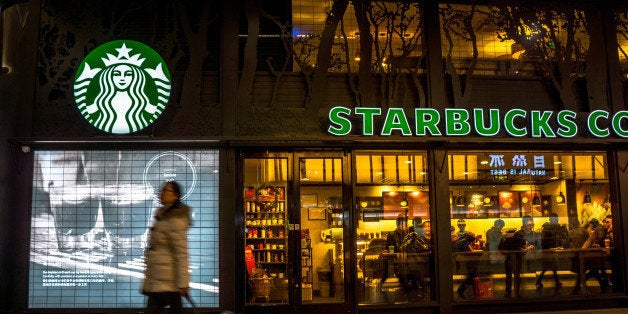 BEIJING, CHINA - 2014/12/12: A girl pulls her luggage past a Starbucks coffee shop in Beijing South railway station. There are totally six Starbucks shops in this railway station. At an investors' meeting held in its China headquarters on the early Dec, Starbucks explained its speedy expansion plan in China to extend its network to 3,400 stores all over the country over the next five years, which means the company's will add 400 stores every year for the next five years. In 2014, Starbucks has opened 317 new stores in China. (Photo by Zhang Peng/LightRocket via Getty Images)