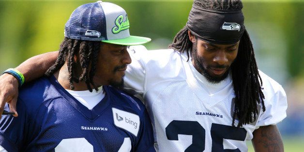 Seattle Seahawks running back Marshawn Lynch, left, walks off the field with cornerback Richard Sherman, right, after NFL Football training camp, Friday, Aug. 1, 2014, in Renton, Wash. Friday was Lynch's first day attending training camp after staying away due to contract issues. (AP Photo/Ted S. Warren)