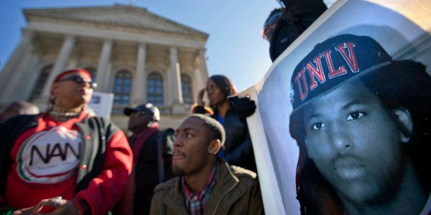 An image of Kendrick Johnson, the south Georgia teenager found dead inside a rolled-up wrestling mat in his school, is displayed on a banner, as demonstrators attend a "Who Killed K.J." rally, Wednesday, Dec. 11, 2013, in Atlanta. Lawyers for the parents of 17-year-old Kendrick Johnson are calling on the governor to order a coroner's inquest into his death. The body of Johnson was found Jan. 11, and sheriff's investigators concluded that he died in a freak accident. Johnson's parents insist someone must have killed him. (AP Photo/David Goldman)