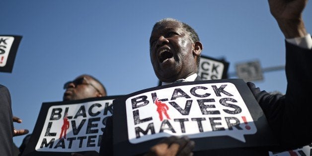 Men holding signs reading 'Black Lives Matter' march in the 30th annual Kingdom Day Parade in honor of Dr. Martin Luther King Jr., January 19, 2015 in Los Angeles, California. 2015 is the 50th anniversary of the historic 1965 Selma to Montgomery Alabama freedom marches which played a pivotal role in the civil rights struggle for racial equality in the U.S. AFP PHOTO / ROBYN BECK (Photo credit should read ROBYN BECK/AFP/Getty Images)