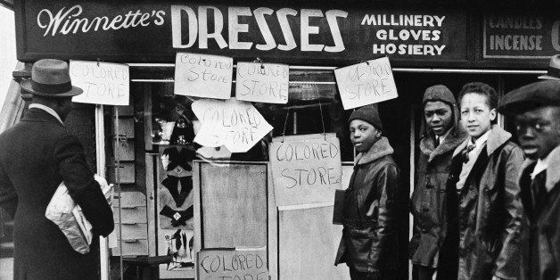 The proprietor of this store, who hastily plastered his display window with signs proclaiming it a 'colored store,' saved this shop from destruction, when rioting African-Americans went through New York's 'black belt' on March 19, 1935, fighting police and shattering store windows. This picture shows the storefront, the center of interest for a group for African-American boys. (AP Photo)