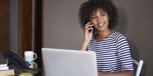 Cropped shot of a young woman sitting at a desk talking on a mobile phone