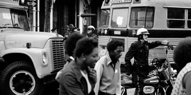 Bused black schoolchildren arrive with police escort at South Boston High School during court-ordered desegregation crisis, S