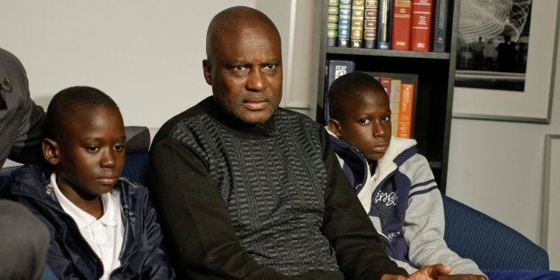 Amadou Drame, 11, and brother Pape Drame, 13, right, listen as their father, Ousmane Drame, responds to questions during a ne