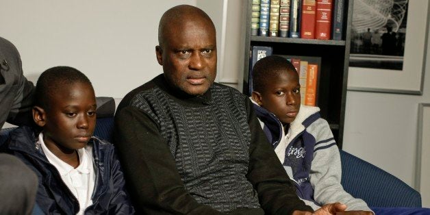 Amadou Drame, 11, and brother Pape Drame, 13, right, listen as their father, Ousmane Drame, responds to questions during a news interview Tuesday, Oct. 28, 2014, in New York. New York City school officials on Monday warned principals to be on the lookout for bullying of West African students after the two brothers from Senegal reported being taunted with chants of "Ebola" and attacked. (AP Photo/Frank Franklin II)