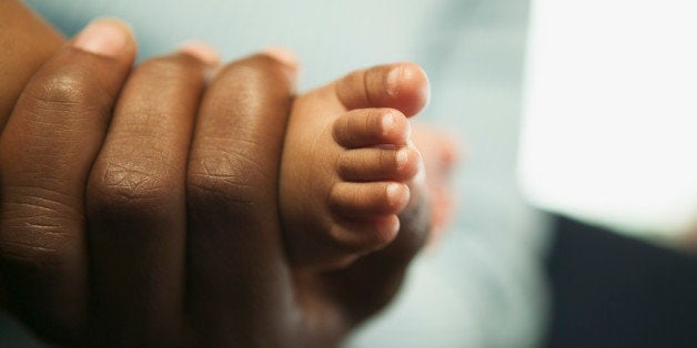 A mother holding her baby daughter's foot.