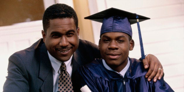 Portrait of a teenage graduate sitting with his father