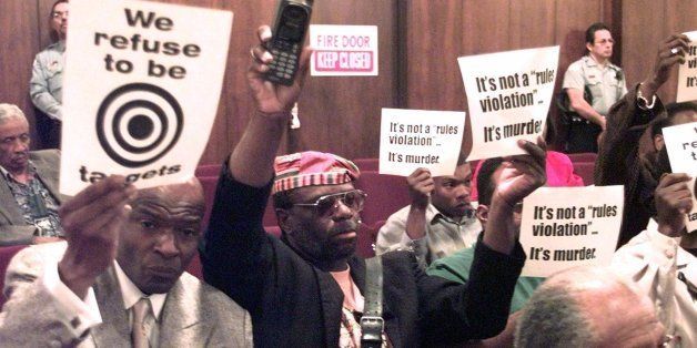 Dr. Nenehemiah Russell, left, from the adhoc committee to end police brutality, and a demonstrator holding a cell phone, protest during a Chicago City Council meeting, Thursday, June 17, 1999, held on two recent police shootings of unarmed people Thursday. One of those killed, LaTanya Haggerty, was allegedly shot as she reached for her cell phone. (AP Photo/Charles Bennett)