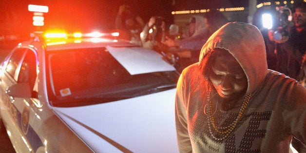 FERGUSON, MO - MARCH 11: Protestors demonstrate by sitting on a police car during a protest outside the Ferguson Police Department on March11, 2015 in Ferguson, MO. Protests erupted after the announcement of the resignation of Ferguson Police Chief Tom Jackson earlier in the day. (Photo by Michael B. Thomas/Getty Images)