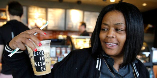 Larenda Myres holds an iced coffee drink with a "Race Together" sticker on it at a Starbucks store in Seattle, Wednesday, March 18, 2015. Starbucks CEO Howard Schultz announced earlier in the day at the company's annual shareholder meeting that participating baristas at stores in the U.S. will be putting the stickers on cups and also writing the words "#RaceTogether" for customers in an effort to raise awareness and discussion of race relations. (AP Photo/Ted S. Warren)
