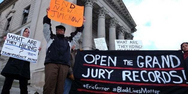 Protesters display a banner and placards during a demonstration outside the courthouse in New York's borough of Staten Island on January 5, 2015, before a hearing in a state lawsuit seeking the release of grand jury proceedings concerning the death of Eric Garner. Garner, a father of six who was suspected of illegally selling cigarettes, was wrestled to the ground by several white police officers after resisting arrest on Staten Island on July 17, 2014. Classified as a homicide by the New York medical examiner's office, his death set off intense reactions and several protests in New York reminiscent of those in Ferguson, Missouri, over the August 9 police shooting of unarmed black teenager Michael Brown. AFP PHOTO/JEWEL SAMAD (Photo credit should read JEWEL SAMAD/AFP/Getty Images)