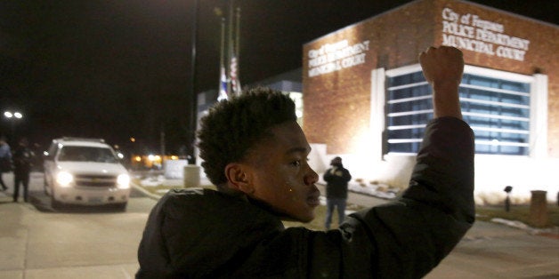 Clifton Kinnie joins protesters as they block traffic on the street outside the Ferguson, Mo., police department Wednesday, March 4, 2015, in Ferguson. The Justice Department on Wednesday cleared a white former Ferguson police officer in the fatal shooting of an unarmed black 18-year-old, but also issued a scathing report calling for sweeping changes in city law enforcement practices it called discriminatory and unconstitutional. (AP Photo/Charles Rex Arbogast)