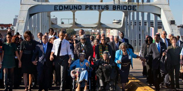 President Barack Obama, fourth from left, walks holding hands with Amelia Boynton Robinson, who was beaten during "Bloody Sunday," as they and the first family and others including Rep. John Lewis, D-Ga, left of Obama, walk across the Edmund Pettus Bridge in Selma, Ala,. for the 50th anniversary of the landmark event of the civil rights movement, Saturday, March 7, 2015. At far left is Sasha Obama and at far right is former first lady Laura Bush. Adelaide Sanford also sits in a wheelchair. (AP Photo/Jacquelyn Martin)