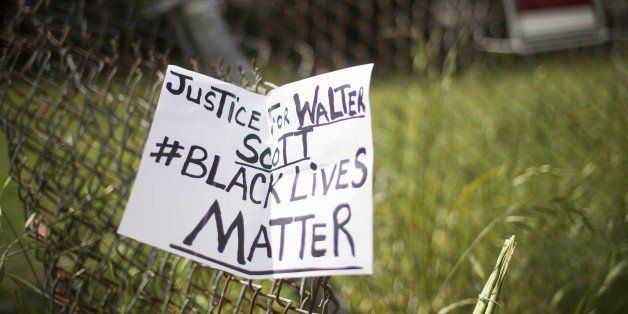 A placard is tied to a fence outside the vacant lot where Walter Scott, the 50-year-old man who was fired at eight times was killed as he ran away from an officer after a traffic stop in North Charleston, South Carolina on April 8, 2015. Police officer Michael Slager,33, who fatally shot Scott in the US city of North Charleston has been fired after he was charged with murder, the mayor said. Speaking at a highly charged press conference frequently interrupted by residents angered at America's latest high-profile police killing of a black man, Mayor Keith Summey said the city had moved quickly to fire the officer after Saturday's shooting. AFP PHOTO/JIM WATSON (Photo credit should read JIM WATSON/AFP/Getty Images)