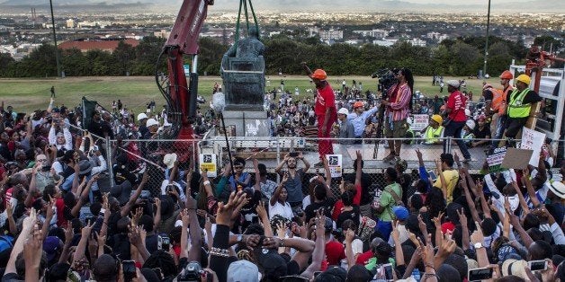 CAPE TOWN, SOUTH AFRICA - APRIL 09: Students cheer as the Cecil Rhodes statue is being removed from the University of Cape Town on April 9, 2015 in Cape Town, South Africa. The statue of British colonialist Cecil John Rhodes was removed from the University of Cape Town as a result of a month long protest by students citing the statue 'great symbolic power' which glorified someone 'who exploited black labour and stole land from indigenous people'. (Photo by Charlie Shoemaker/Getty Images)