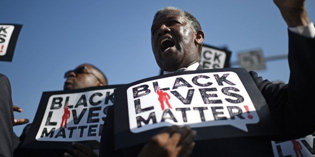 Men holding signs reading 'Black Lives Matter' march in the 30th annual Kingdom Day Parade in honor of Dr. Martin Luther King Jr., January 19, 2015 in Los Angeles, California. 2015 is the 50th anniversary of the historic 1965 Selma to Montgomery Alabama freedom marches which played a pivotal role in the civil rights struggle for racial equality in the U.S. AFP PHOTO / ROBYN BECK (Photo credit should read ROBYN BECK/AFP/Getty Images)