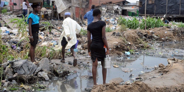 People walk past shanty homes at Badia East slums in Lagos on August 12, 2013. Forced evictions in Nigeria's largest city Lag