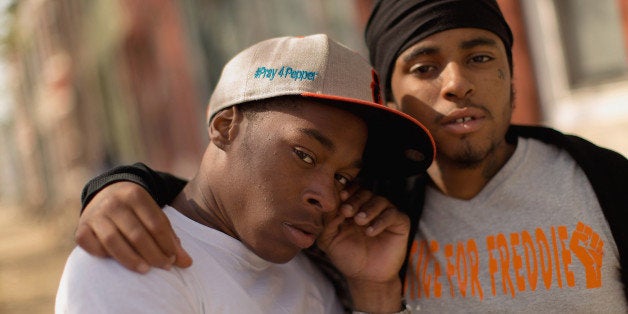 BALTIMORE, MD - APRIL 21: Young men show their support for Freddie Gray by wearing clothes printed with '#Pray4Pepper' and '#JusticeForFreddie' in the Sandtown neighborhood where April 21, 2015 in Baltimore, Maryland. Gray, whose nickname was Pepper, was a 25-year-old black man who lived in this neighborhood and was arrested for possessing a switch blade knife April 12 outside the Gilmor Homes housing project on Baltimore's west side. According to his attorney, Gray died a week later in the hospital from a severe spinal cord injury he received while in police custody. (Photo by Chip Somodevilla/Getty Images)