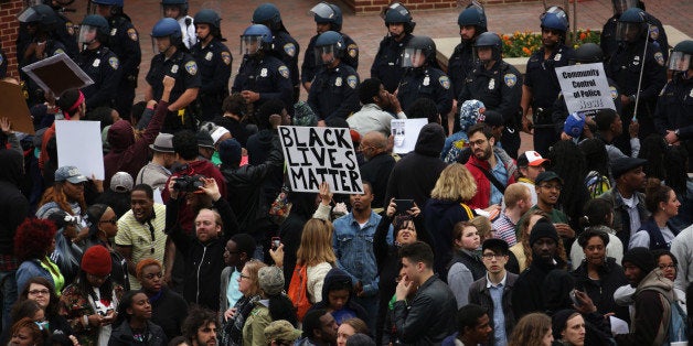 BALTIMORE, MD - APRIL 25: Protesters hold signs as they stand off with the police at Camden Yard during a march in honor of F