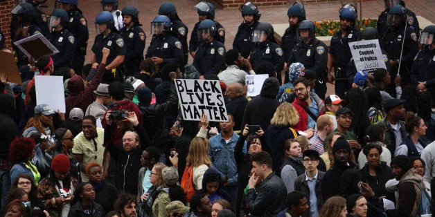 BALTIMORE, MD - APRIL 25: Protesters hold signs as they stand off with the police at Camden Yard during a march in honor of Freddie Gray on April 25, 2015 in Baltimore, Maryland. Gray, 25, was arrested for possessing a switch blade knife outside the Gilmor Homes housing project on Baltimore's west side on April 12. According to his attorney, Gray died a week later in the hospital from a severe spinal cord injury he received while in police custody. (Photo by Alex Wong/Getty Images)