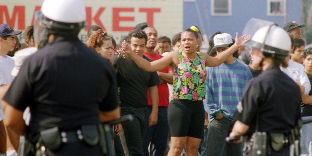 A woman yells at Los Angeles police officers who stand guard outside a shopping center, 30 April 1992, in Los Angeles. The acquittal of four police officers in the beating of Rodney King led to widespread anger and rioting. (Photo credit should read DON EMMERT/AFP/Getty Images)