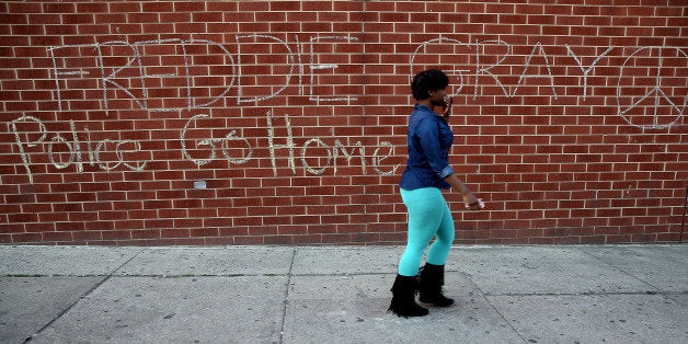 BALTIMORE, MD - MAY 02: A woman walks by a tagging that reads 'Freddie Gray...Police Go Home' a day after Baltimore authoriti