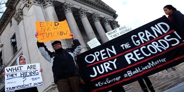 Protesters display a banner and placards during a demonstration outside the courthouse in New York's borough of Staten Island on January 5, 2015, before a hearing in a state lawsuit seeking the release of grand jury proceedings concerning the death of Eric Garner. Garner, a father of six who was suspected of illegally selling cigarettes, was wrestled to the ground by several white police officers after resisting arrest on Staten Island on July 17, 2014. Classified as a homicide by the New York medical examiner's office, his death set off intense reactions and several protests in New York reminiscent of those in Ferguson, Missouri, over the August 9 police shooting of unarmed black teenager Michael Brown. AFP PHOTO/JEWEL SAMAD (Photo credit should read JEWEL SAMAD/AFP/Getty Images)