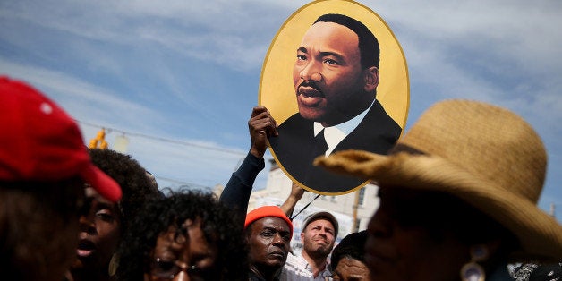 SELMA, AL - MARCH 08: A marcher holds a picture of Dr. Martin Luther King Jr. before walking across the Edmund Pettus Bridge during the 50th anniversary commemoration of the Selma to Montgomery civil rights march on March 8, 2015 in Selma, Alabama. Tens of thousands of people gathered in Selma to commemorate the 50th anniversary of the famed civil rights march from Selma to Montgomery that resulted in a violent confrontation with Selma police and State Troopers on the Edmund Pettus Bridge on March 7, 1965. (Photo by Justin Sullivan/Getty Images)