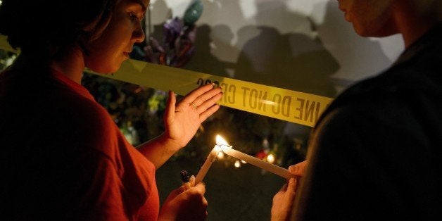 Olina Ortega (L) and Austin Gibbs light candles at a makeshift memorial outside the Emanuel AME Church in Charleston, South Carolina on June 18, 2015. Police captured the white suspect, 21-year-old Dylann Roof, the main suspect in a gun massacre at one of the oldest black churches in the United States, the latest deadly assault to feed simmering racial tensions. AFP PHOTO/BRENDAN SMIALOWSKI (Photo credit should read BRENDAN SMIALOWSKI/AFP/Getty Images)