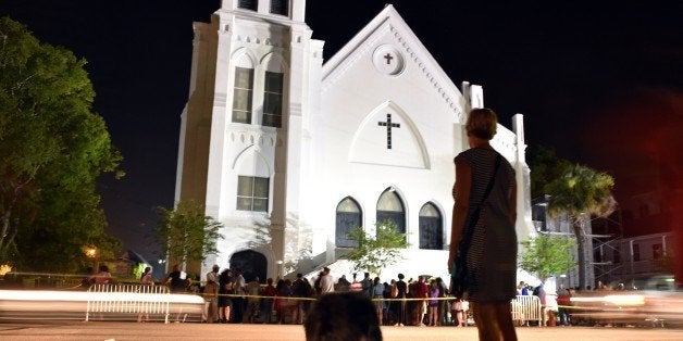 A woman pauses in respect as she passes next to Emanuel AME Church in Charleston, South Carolina on June 18, 2015. Police captured the white suspect in a gun massacre at one of the oldest black churches in the United States, the latest deadly assault to feed simmering racial tensions. Police detained 21-year-old Dylann Roof, shown wearing the flags of defunct white supremacist regimes in pictures taken from social media, after nine churchgoers were shot dead during bible study on June 17, 2015. AFP PHOTO / MLADEN ANTONOV (Photo credit should read MLADEN ANTONOV/AFP/Getty Images)