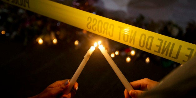 Olina Ortega, left, and Austin Gibbs light candles at a sidewalk memorial in front of Emanuel AME Church where people were killed by a white gunman Wednesday during a prayer meeting inside the historic black church in Charleston, S.C., Thursday, June 18, 2015. (AP Photo/David Goldman)