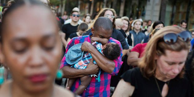 David Allen, of Charleston, S.C., holds his five-month-old son Elijah during a moment of prayer at a vigil in memory of the Emanuel AME Church shooting victims held in front of the Daughters of the Confederacy building Saturday, June 20, 2015, in Charleston, S.C. (AP Photo/David Goldman)