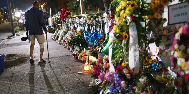 CHARLESTON, SC - JUNE 20: Monte Talmadge walks past the memorial on the sidewalk in front the Emanuel African Methodist Episcopal Church after a mass shooting at the church killed nine people on June 20, 2015 in Charleston, United States. Dylann Roof, 21 years old, has been charged with killing nine people during a prayer meeting in the church, which is one of the nation's oldest black churches in Charleston. (Photo by Joe Raedle/Getty Images)