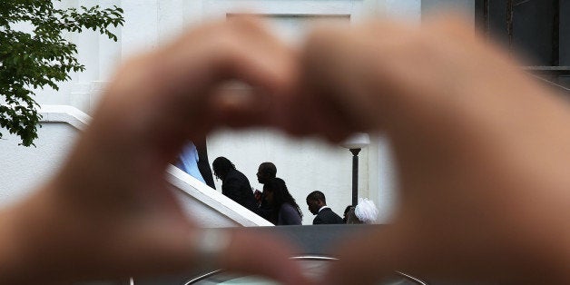 CHARLESTON, SC - JUNE 27: Heather Hayward forms a heart with her hands as mourners file in for the funeral of Cynthia Hurd, 54, at the Emanuel African Methodist Episcopal Church where she was killed along with eight others in a mass shooting at the church on June 27, 2015 in Charleston, South Carolina. Suspected shooter Dylann Roof, 21 years old, is accused of killing nine people on June 17th during a prayer meeting in the church, which is one of the nation's oldest black churches in Charleston. (Photo by Joe Raedle/Getty Images)