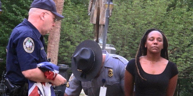 Bree Newsome of Charlotte, N.C., right, is taken into custody after she removed the Confederate battle flag from a monument in front of the South Carolina Statehouse in Columbia, S.C., on Saturday, June, 27, 2015. The flag was raised again by capitol workers about 45 minutes later. (AP Photo/Bruce Smith)