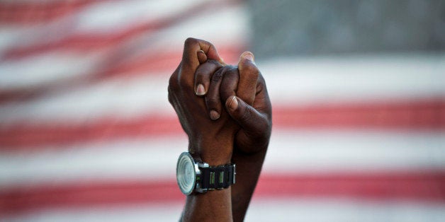 People join hands against the backdrop of an American flag as thousands of marchers meet in the middle of Charleston's main bridge in a show of unity after nine black church parishioners were gunned down during a Bible study, Sunday, June 21, 2015, in Charleston, S.C. (AP Photo/David Goldman)