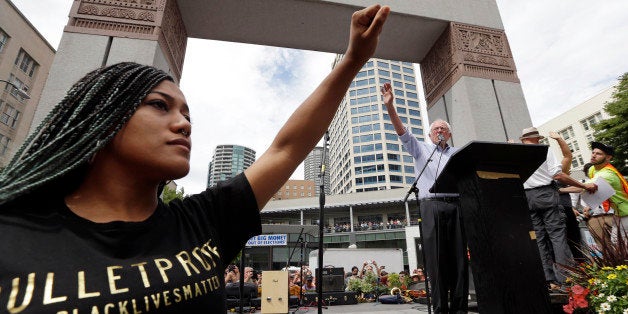 Mara Jacqueline Willaford, left, holds her fist overhead as Democratic presidential candidate Sen. Bernie Sanders, I-Vt., wav