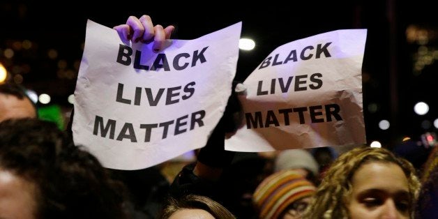 Protestors hold up signs while chanting "Black Lives Matter" during a demonstration against the deaths of two unarmed black m