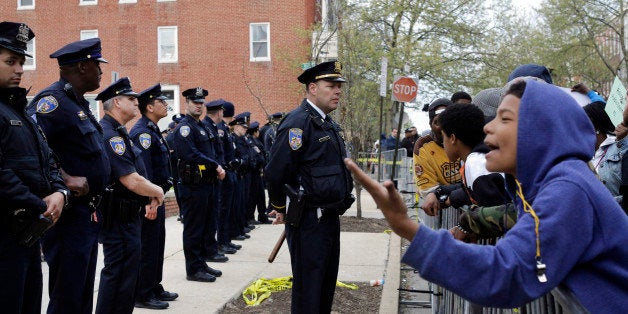 Members of the Baltimore Police Department stand guard outside the department's Western District police station during a prot