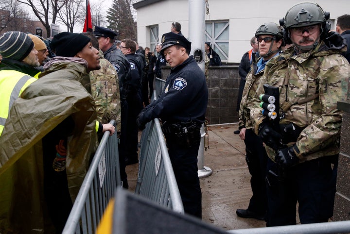 A Black Lives Matter supporter, left, talks to Minneapolis police guarding the Fourth Precinct entrance, Wednesday, Nov. 18, 2015, in Minneapolis. It was the fourth day of protests of the killing of 24-year-old Jamar Clark, an unarmed black man, by a Minneapolis police officer. (AP Photo/Jim Mone)